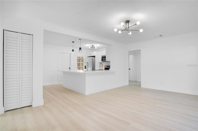 kitchen with white cabinets, stainless steel appliances, hanging light fixtures, kitchen peninsula, and light hardwood / wood-style flooring