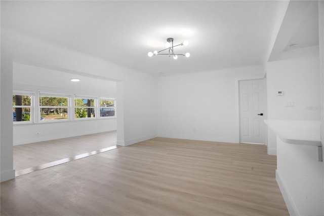 unfurnished room with a chandelier and light hardwood / wood-style flooring