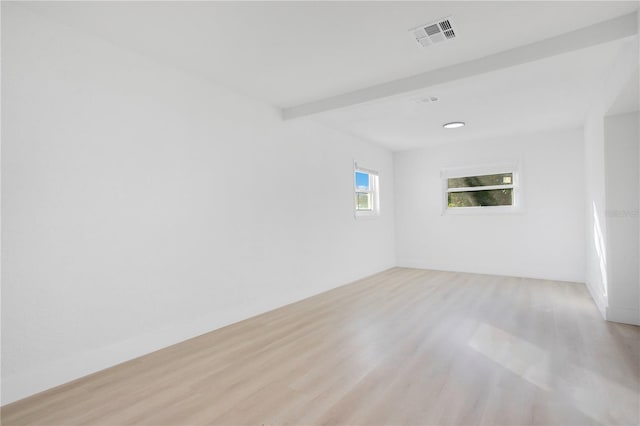 unfurnished room with beam ceiling and light wood-type flooring