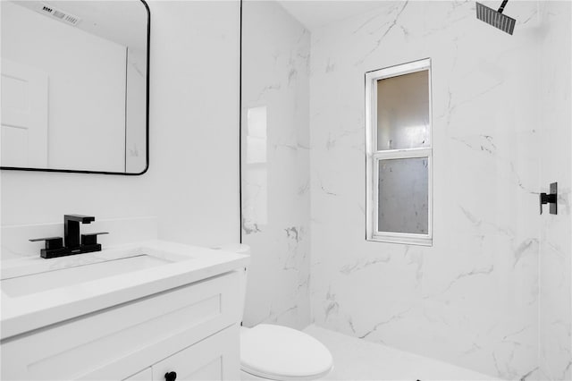 bathroom featuring vanity, toilet, and a tile shower