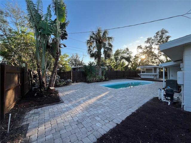 view of swimming pool with central air condition unit and a patio