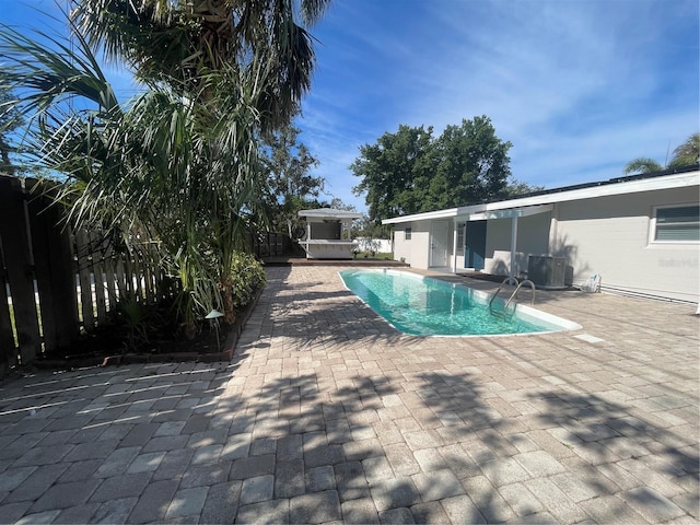 view of swimming pool with central air condition unit, a patio area, and a jacuzzi