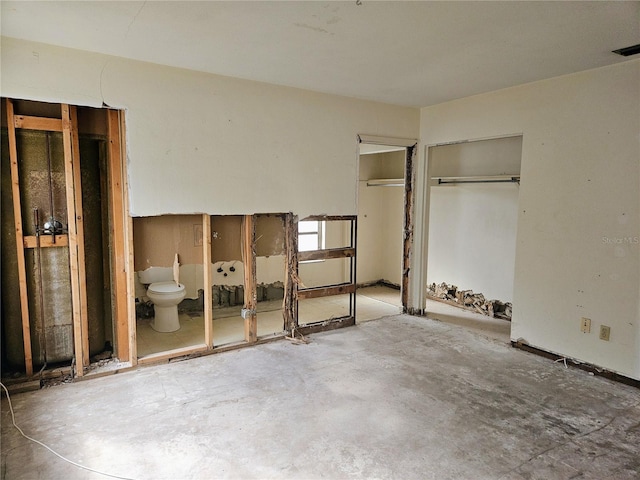 unfurnished bedroom featuring concrete flooring and ensuite bath