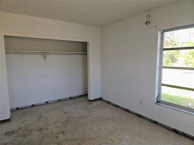 unfurnished bedroom featuring light carpet, multiple windows, and a closet