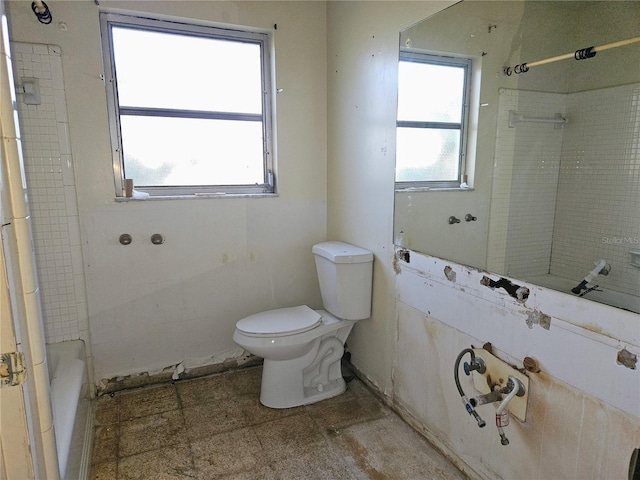 bathroom with toilet and tiled shower / bath