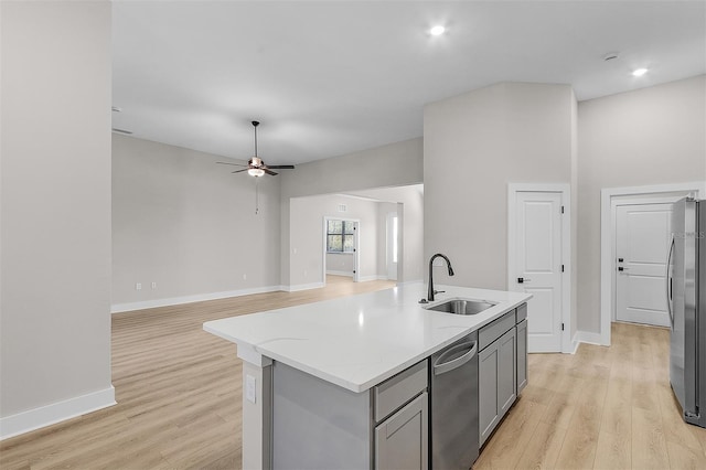 kitchen featuring sink, gray cabinetry, stainless steel appliances, an island with sink, and light wood-type flooring