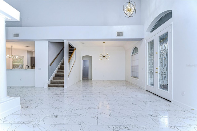 foyer with a chandelier, marble finish floor, visible vents, and stairway