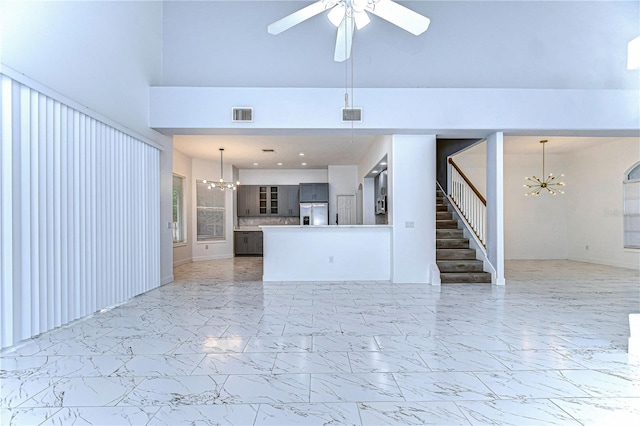 unfurnished living room featuring stairs, marble finish floor, ceiling fan with notable chandelier, and visible vents