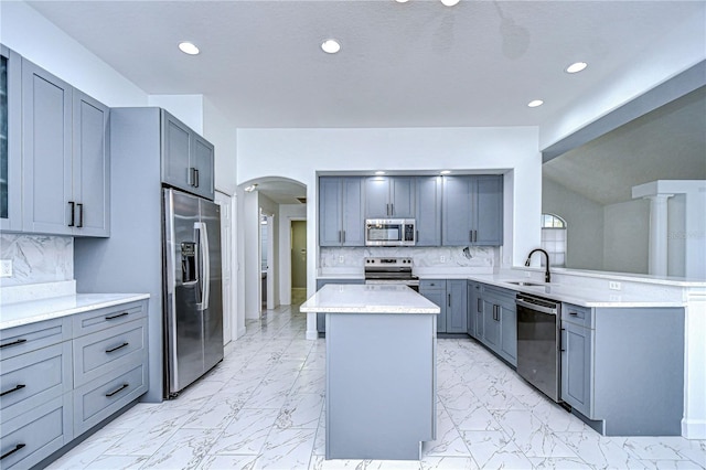 kitchen featuring appliances with stainless steel finishes, a center island, marble finish floor, light countertops, and a sink