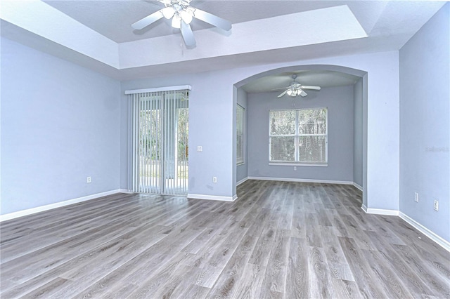 spare room featuring ceiling fan, plenty of natural light, and baseboards