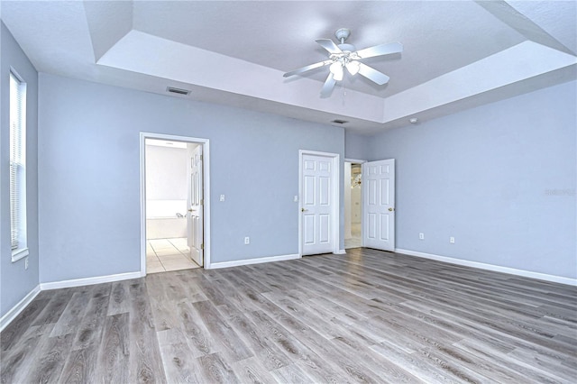 unfurnished bedroom featuring a tray ceiling and baseboards