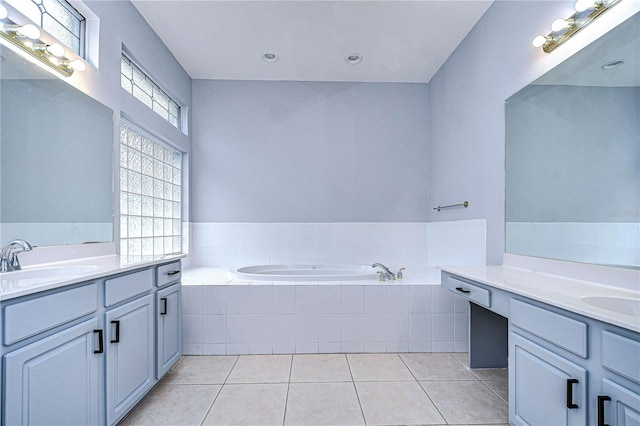 bathroom featuring a garden tub, tile patterned flooring, two vanities, and a sink