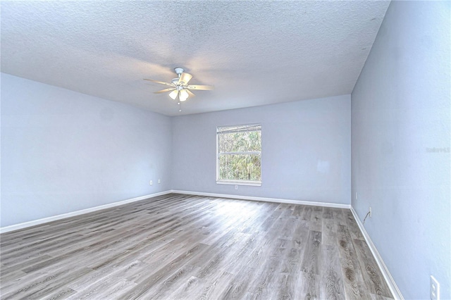 unfurnished room with light wood-style floors, ceiling fan, a textured ceiling, and baseboards