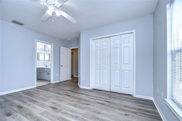 unfurnished bedroom with light wood-style flooring, a sink, visible vents, and baseboards