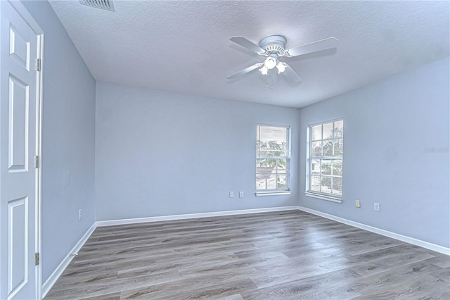 spare room with baseboards, a textured ceiling, a ceiling fan, and wood finished floors