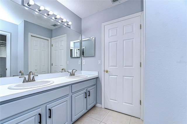 bathroom with double vanity, a closet, a sink, and tile patterned floors