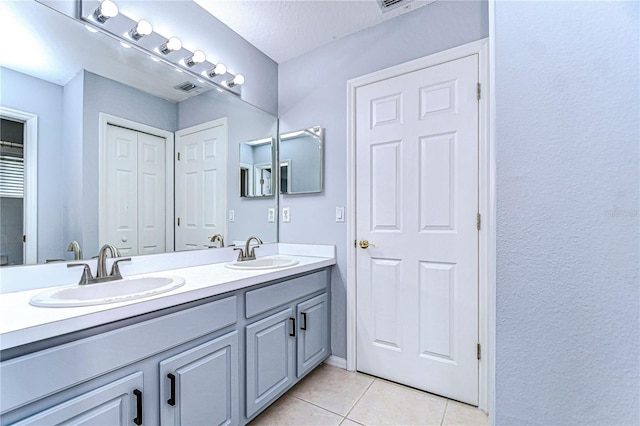 full bathroom with double vanity, a closet, a sink, and tile patterned floors