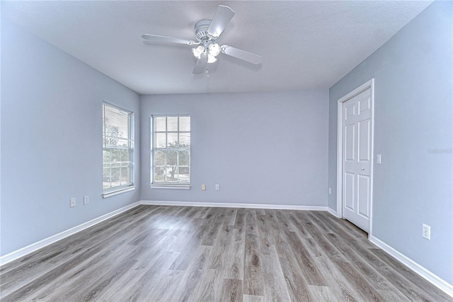 unfurnished room featuring a ceiling fan, light wood-style flooring, and baseboards