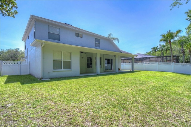 rear view of house featuring stucco siding, a fenced backyard, a patio area, and a yard