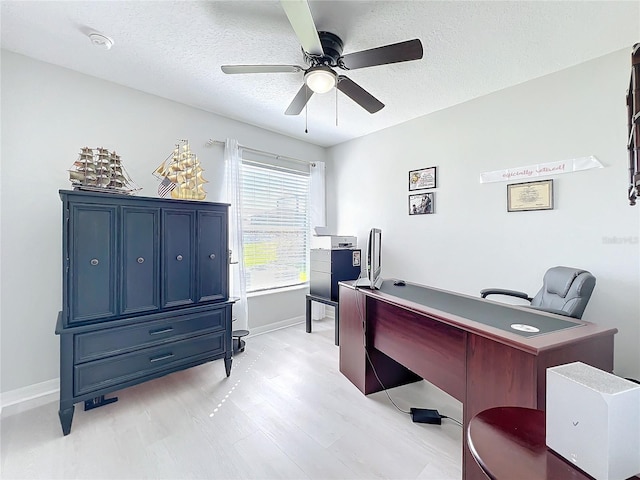 home office featuring a ceiling fan, light wood-type flooring, a textured ceiling, and baseboards