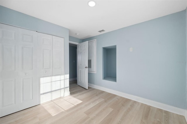 unfurnished bedroom featuring light wood-type flooring and a closet