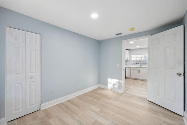 unfurnished bedroom featuring a closet, sink, and light hardwood / wood-style flooring