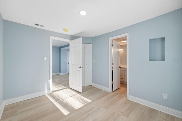 unfurnished bedroom featuring connected bathroom, a closet, and light wood-type flooring