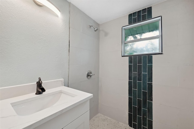 bathroom featuring a tile shower and vanity