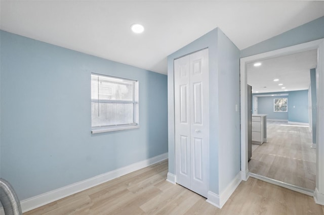 hallway featuring lofted ceiling and light wood-type flooring