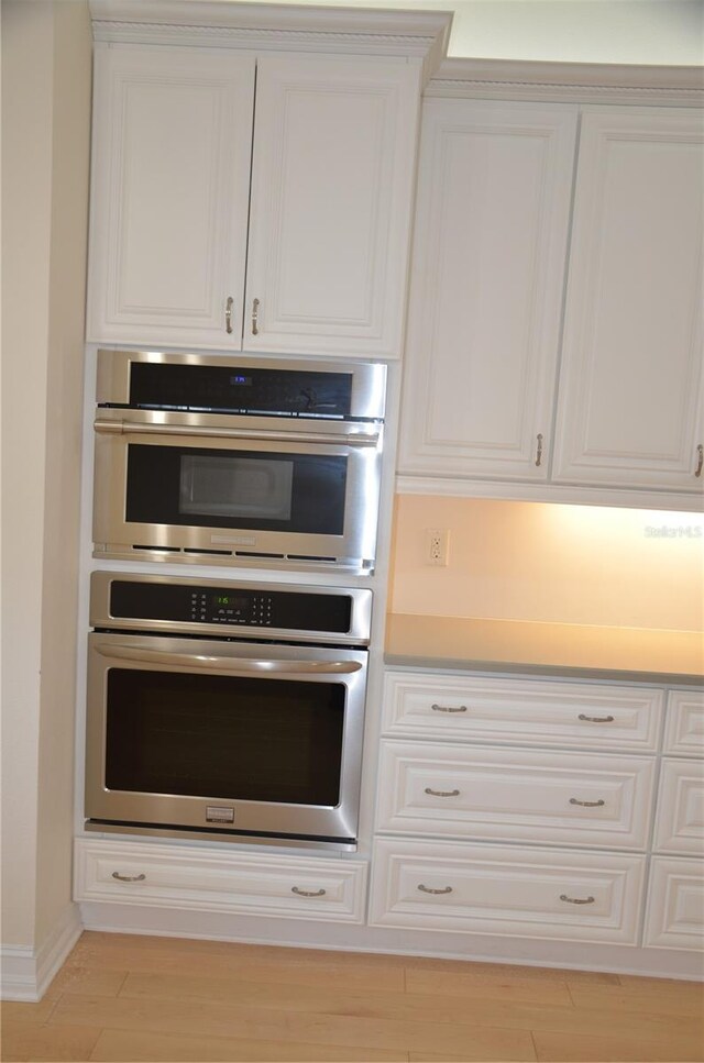 kitchen featuring white cabinetry, light hardwood / wood-style flooring, and stainless steel double oven