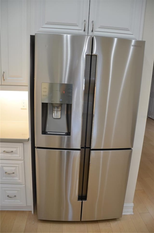 kitchen with stainless steel refrigerator with ice dispenser and white cabinets