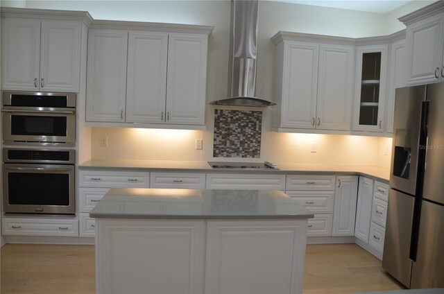 kitchen featuring white cabinetry, light wood-type flooring, appliances with stainless steel finishes, and wall chimney exhaust hood