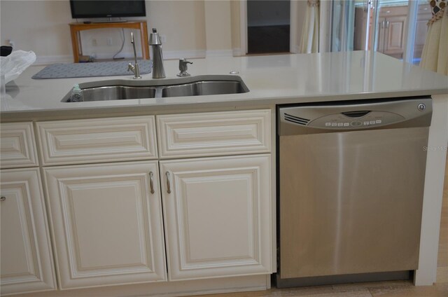 kitchen with stainless steel dishwasher, sink, and cream cabinetry