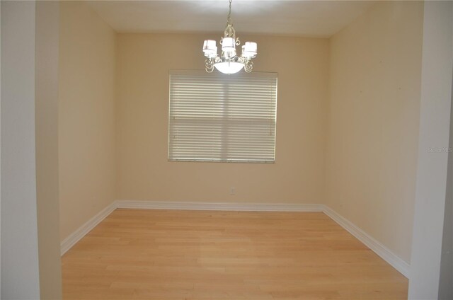 spare room with light wood-type flooring and a chandelier