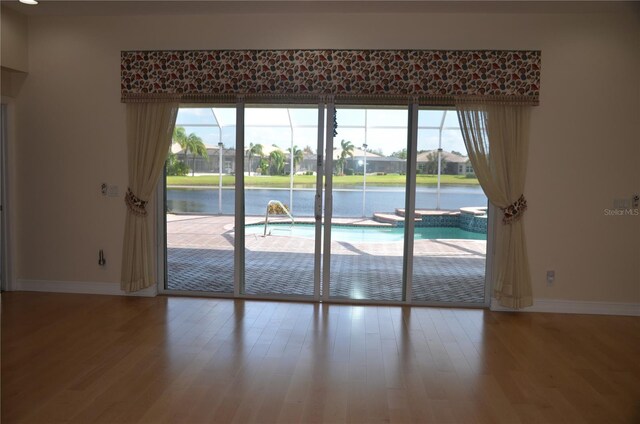 interior space featuring a wealth of natural light, wood-type flooring, and a water view