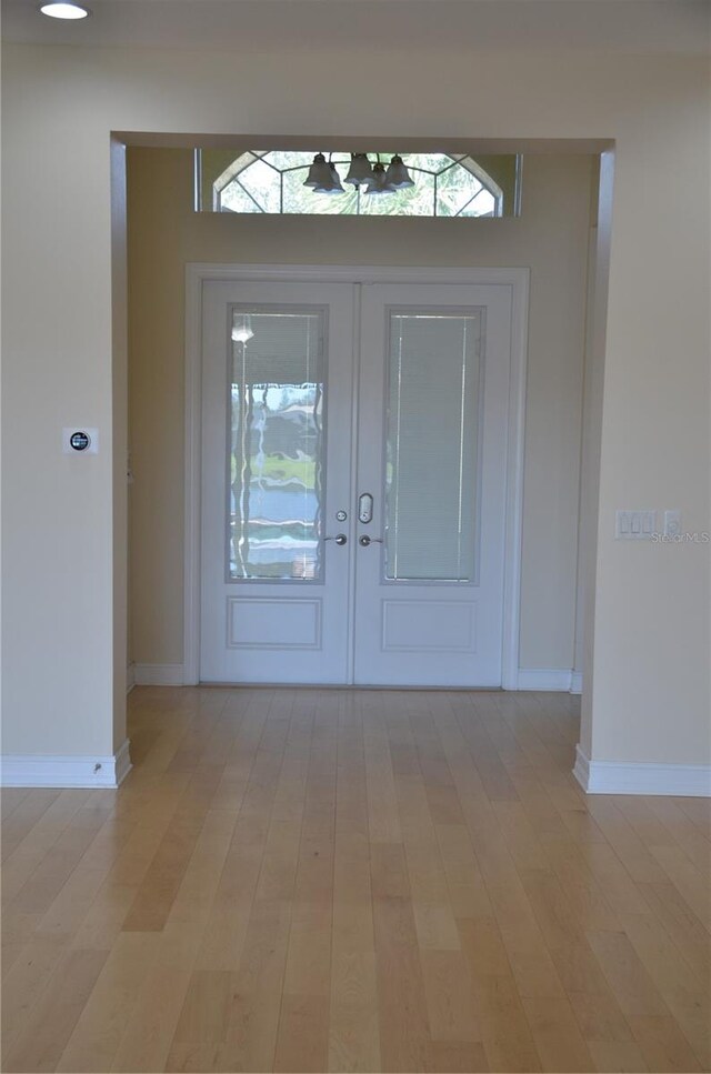 entrance foyer with french doors and light hardwood / wood-style flooring