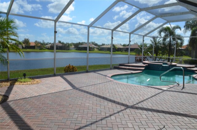 view of swimming pool featuring a water view, glass enclosure, an in ground hot tub, and a patio area