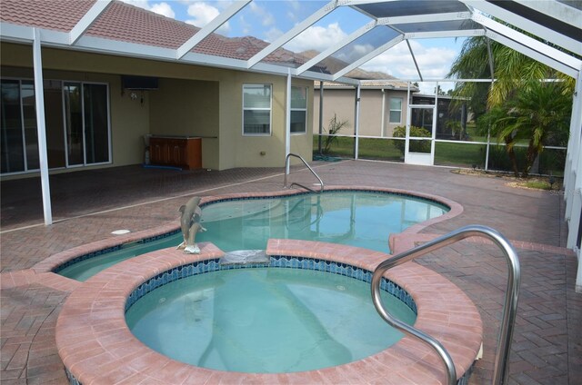 view of pool featuring glass enclosure, a patio, and an in ground hot tub