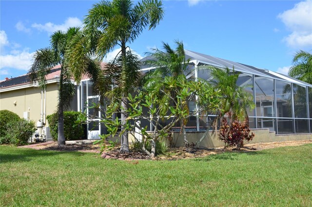 view of side of property featuring a lanai and a yard