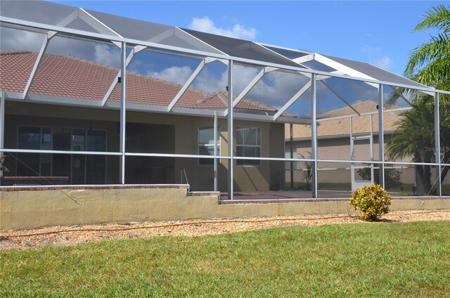 rear view of property with a lanai and a lawn