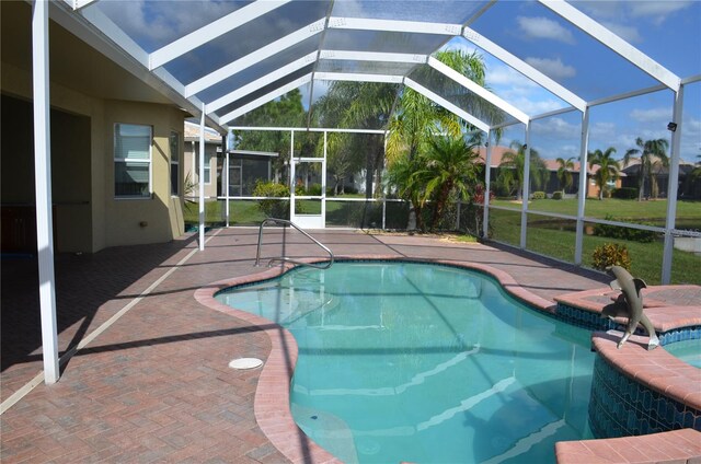 view of swimming pool with a hot tub, a patio, a lawn, and a lanai