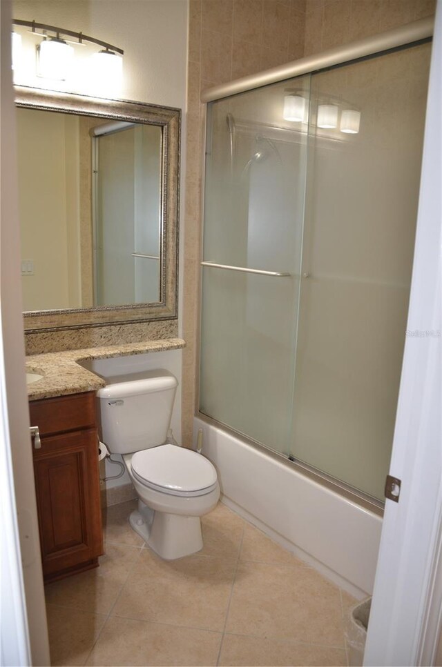 full bathroom with toilet, vanity, bath / shower combo with glass door, and tile patterned flooring