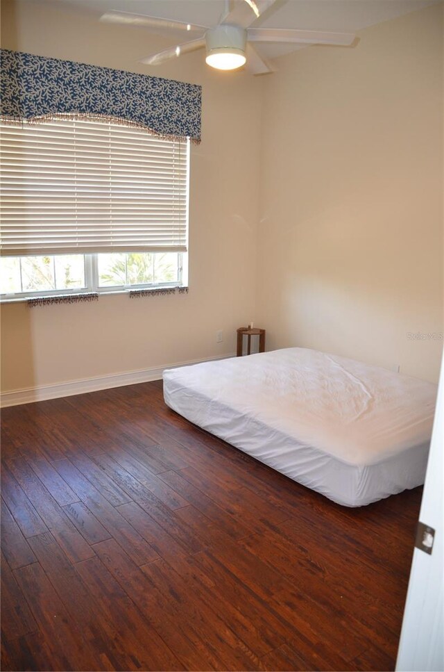 unfurnished bedroom featuring multiple windows, dark hardwood / wood-style flooring, and ceiling fan