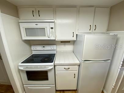 kitchen with tile countertops, white cabinets, and white appliances