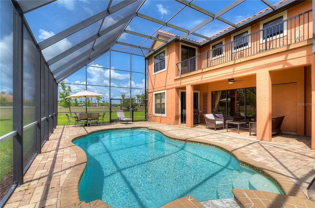 view of swimming pool with a patio, glass enclosure, and ceiling fan