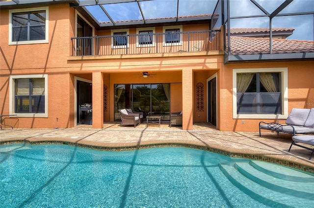 rear view of property featuring a lanai, ceiling fan, a patio area, and a balcony