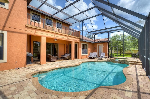 view of pool with a lanai, a patio area, an in ground hot tub, and grilling area