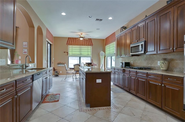 kitchen with ceiling fan, sink, a center island, stainless steel appliances, and backsplash