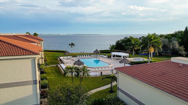 view of swimming pool featuring a yard, a water view, and a patio