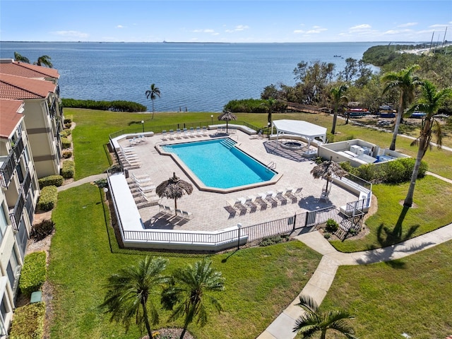 view of swimming pool with a yard, a patio, and a water view